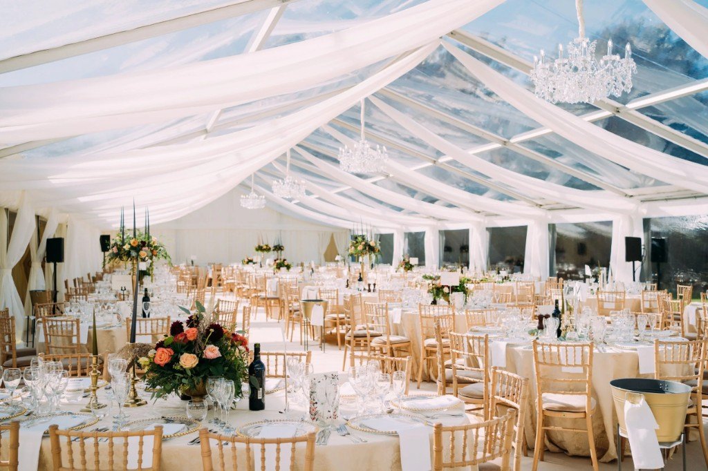 Marquee with flowing ceiling drapes, crystal chandeliers and dressed round tables